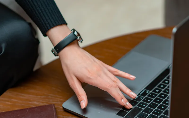 Mano de una mujer sobre una laptop, junto a un pasaporte y unos papeles: el papeleo para formalizar un negocio pequeño en Estados Unidos.